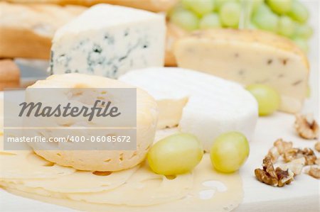 Various Types of Cheese, Grapes and Walnuts on Wooden Chopping Board