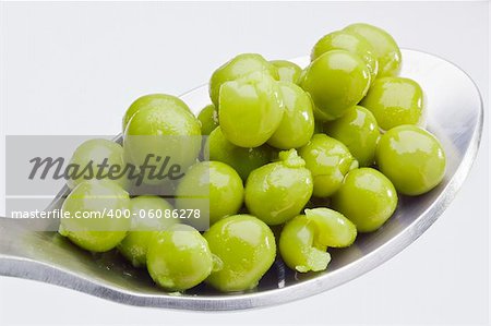 Close-up photograph of green peas on a spoon.