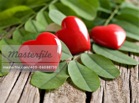 Red heart ornaments on green leaves