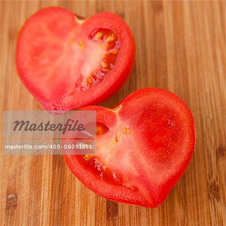 say it with tomatoes - heart-shaped tomato cut in half on a wooden chopping board