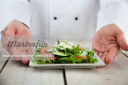 Male chef in restaurant kitchen is garnishing and preparing pasta dish