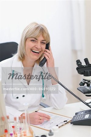 Smiling middle age doctor woman speaking phone
