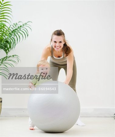 Portrait of mother and baby playing with fitness ball