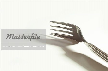 metallic fork and her shadow on the white background