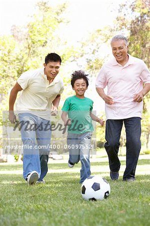 Grandfather With Son And Grandson Playing Football In Park