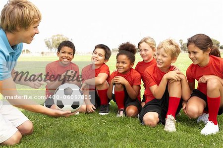 Young Boys And Girls In Football Team  With Coach