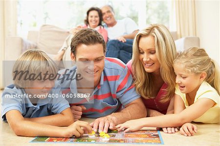 Family Playing Board Game At Home With Grandparents Watching