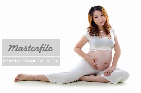 Asian pregnant woman sitting on floor, hand on stomach