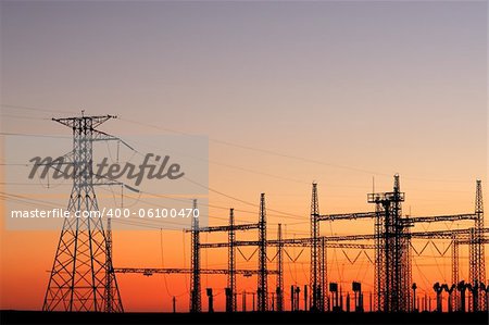 Silhouetted power pylons against a red sky at sunset