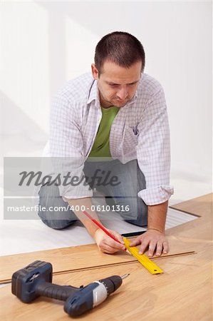 Man laying laminate flooring - measuring a plank