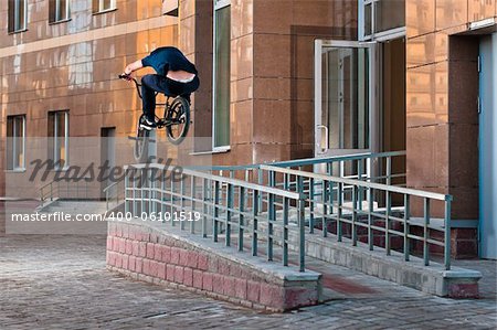 Biker doing high rail hop trick on bmx, back view