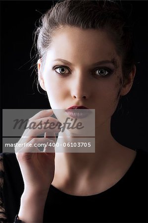 close up portrait of very beautiful young lady actrees over a dark background with dirty make up and fashion light, she is in fornt of the camera, looks in to the lens and her right hand is near the face