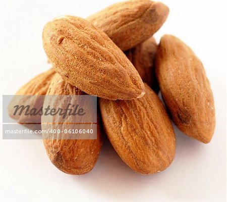 brown raw almonds over white background macro