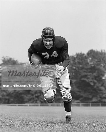 1940s FOOTBALL PLAYER HOLDING FOOTBALL RUNNING FORWARD LOOKING AT CAMERA