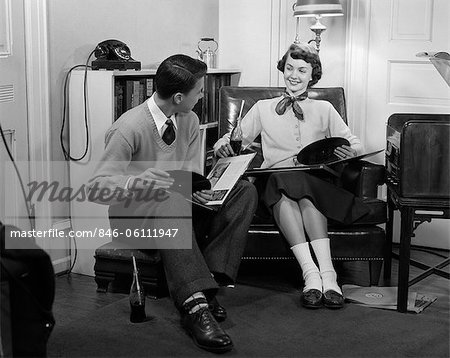 1950s TEEN BOY & GIRL SITTING IN LIVING ROOM DRINKING SODA & LISTENING TO RECORDS