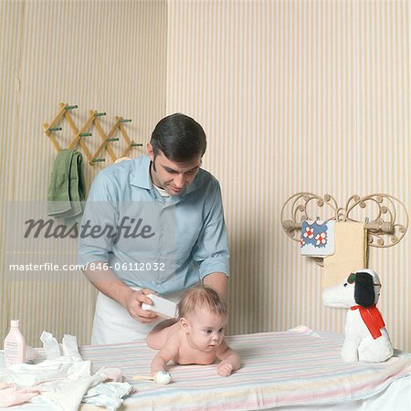 1970s FATHER CHANGING BABY GIRL DIAPER POWDERING BUTT
