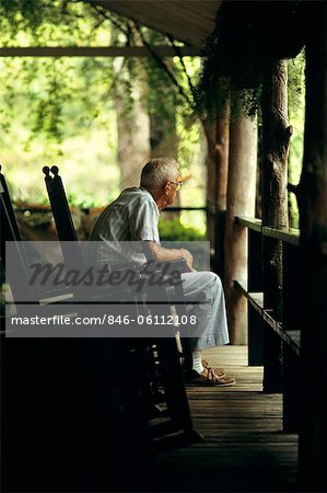 1980s ELDERLY SENIOR MAN SITTING ON PORCH IN ROCKING CHAIR