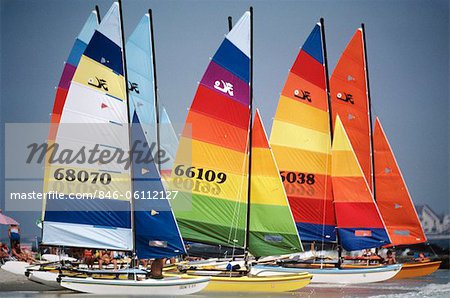 1980 1980s RETRO GROUP OF SAILBOATS WITH COLORFULLY STRIPED SAILS IN WATER