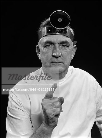 1950s PORTRAIT MAN DOCTOR WEARING EXAMINATION MIRROR POINTING SHAKING FINGER GIVING STERN WARNING LOOKING AT CAMERA