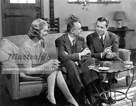 1930s 1940s TWO MEN AND WOMAN SOCIAL GROUP SITTING ON COUCH TALKING INDOOR
