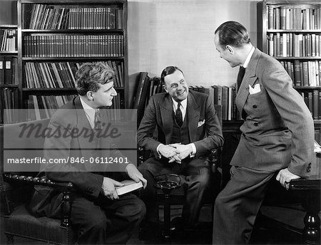 1940s GROUP OF THREE BUSINESSMEN SITTING TOGETHER IN LIBRARY TALKING SMILING