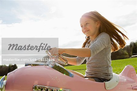 Girl driving toy airplane in field