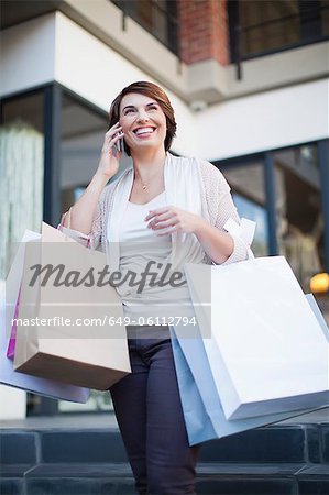Frau am Handy mit Einkaufstaschen
