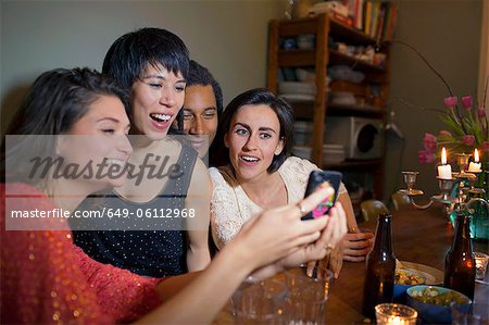 Friends using cell phone at dinner table