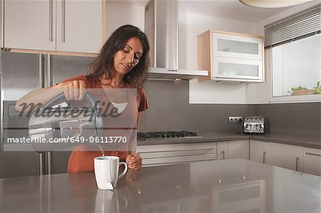 Woman making cup of tea in kitchen