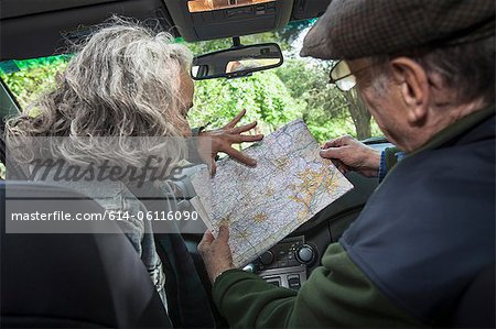 Senior couple in car, looking at map