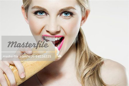 Young woman biting baguette