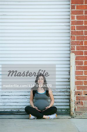 Pregnant young woman sitting cross legged, portrait