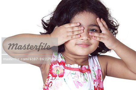 Portrait of a young girl covering her eyes with her hands
