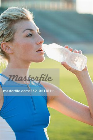 Young woman hydrating, taking break from exercising