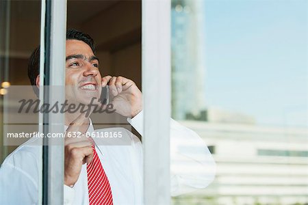 Kaufmann mit Handy im Büro außerhalb der Fenster aus gesehen