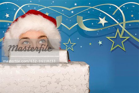 Young woman peeking over stack of Christmas gifts