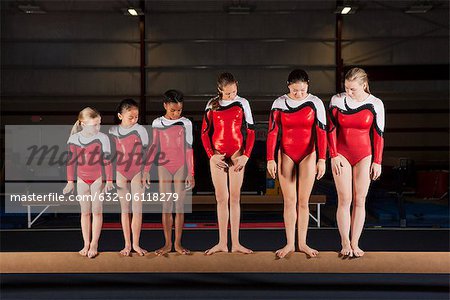 Gymnastes femmes d'âges divers, debout dans une ligne sur la poutre d'équilibre