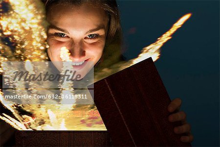 Young woman opening gift box containing glowing fireworks