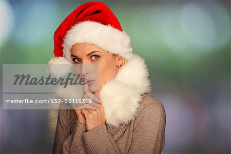 Woman wearing Santa hat, finger on lips, portrait