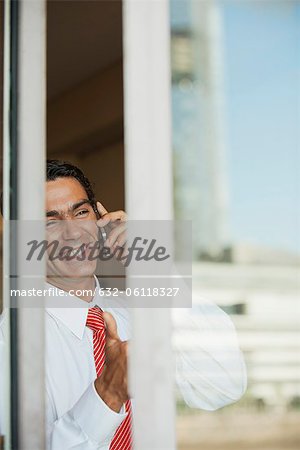 Kaufmann mit Handy im Büro außerhalb der Fenster aus gesehen