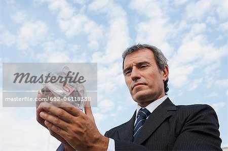 Mature man holding transparent piggy bank filled with euros