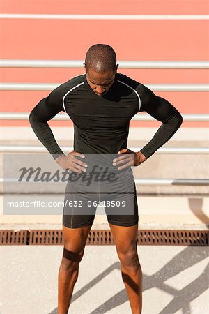 Male athlete standing by running track with head down