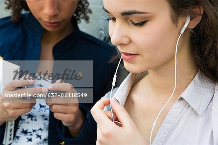 Jeune femme debout avec ami, écoutant les écouteurs