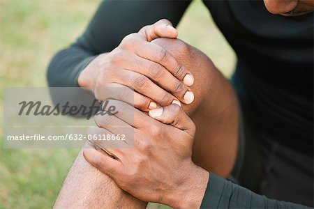 Man holding injured knee, cropped