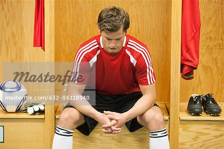 Soccer player sitting alone in locker room