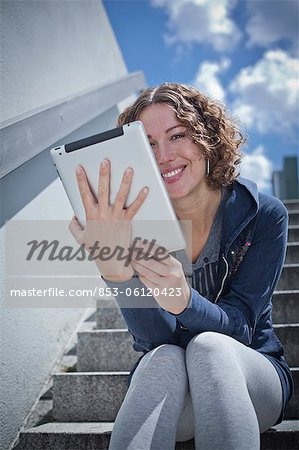 Woman sitting with ipad on stairs