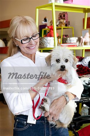 Happy senior woman carrying dog in pet shop