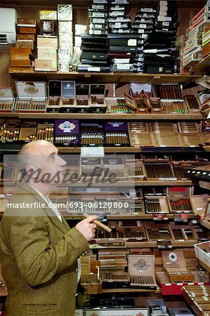 Reife Tabak-Shop-Betreiber, die Zigarren auf dem Display zu betrachten