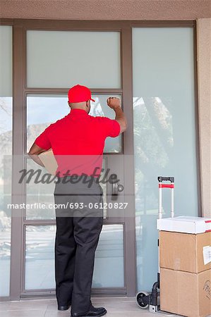 Rear view of a delivery man knocking on door