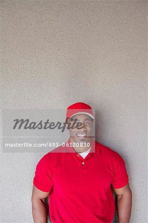 Portrait of a happy African American delivery man against wall